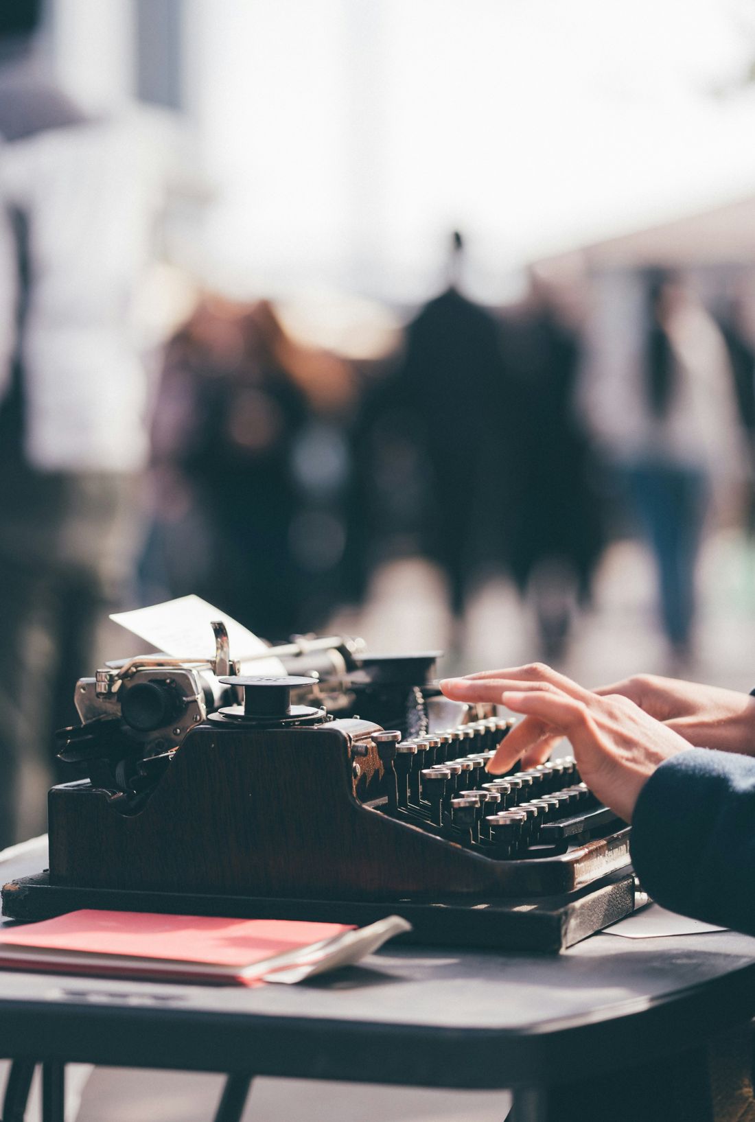 Hands typing on a vintage typewriter at an outdoor market